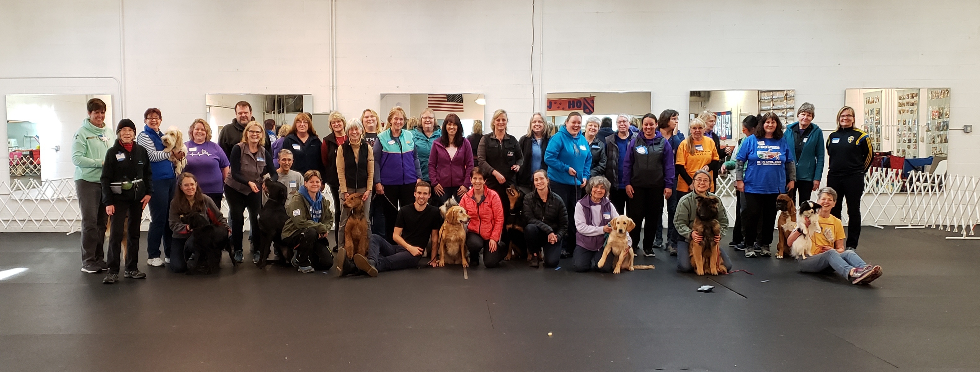 A large group of students and their dogs posing together in the training hall