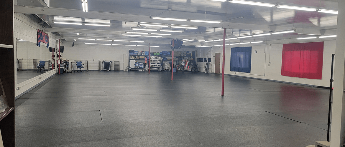 The empty matted training room, with rally and agility equipment stored along the back wall